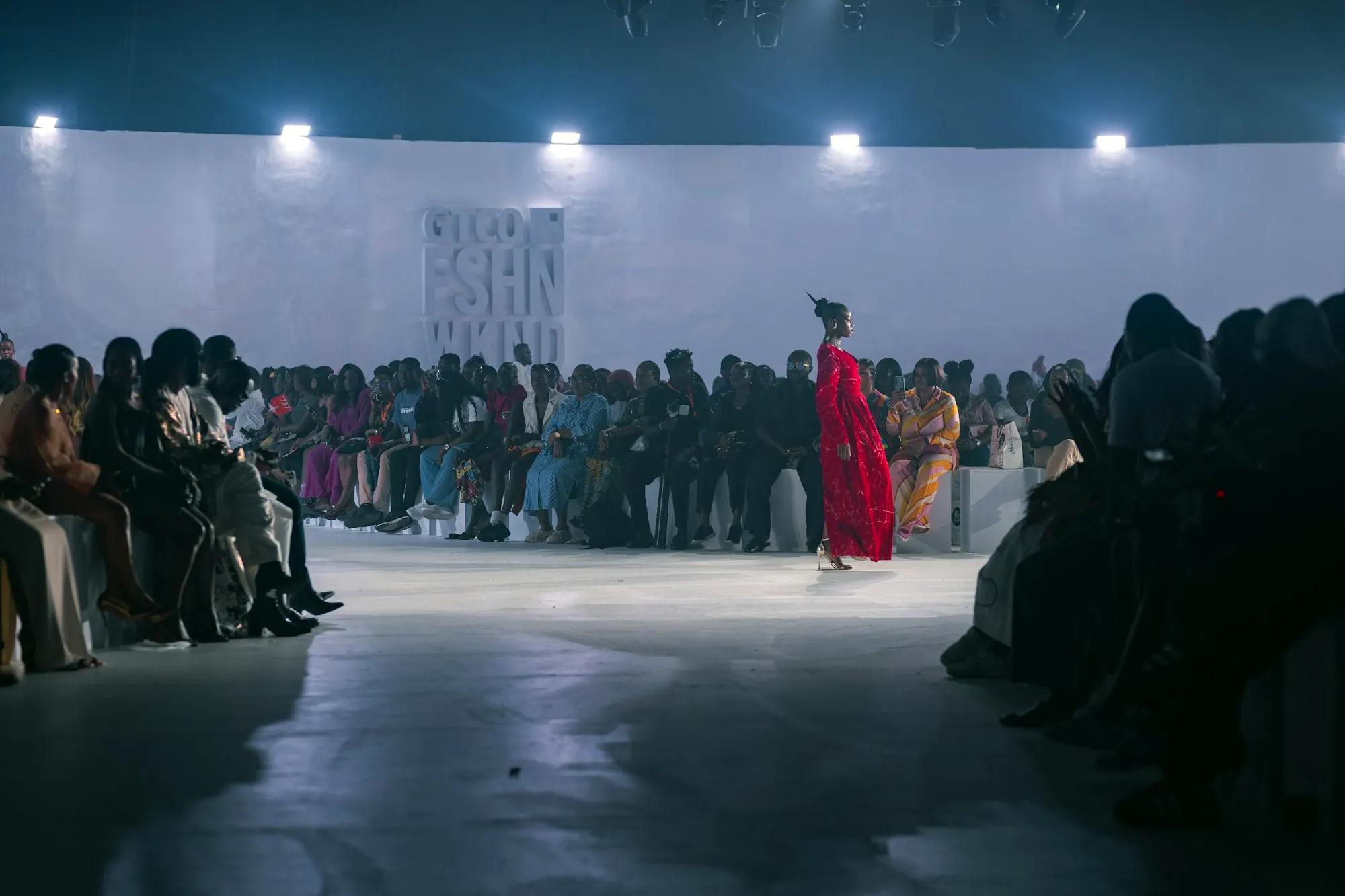 Spectators watching a fashion show from both sides of the runway.