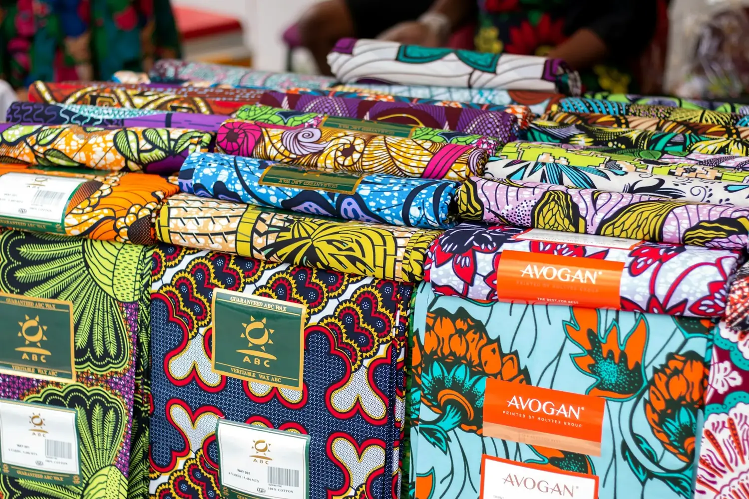 Stacks of brightly patterned African fabrics laid out for sale.