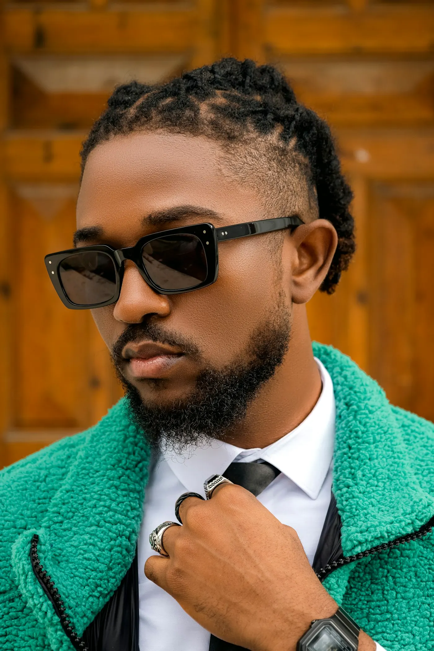 A man in a green coat and sunglasses.