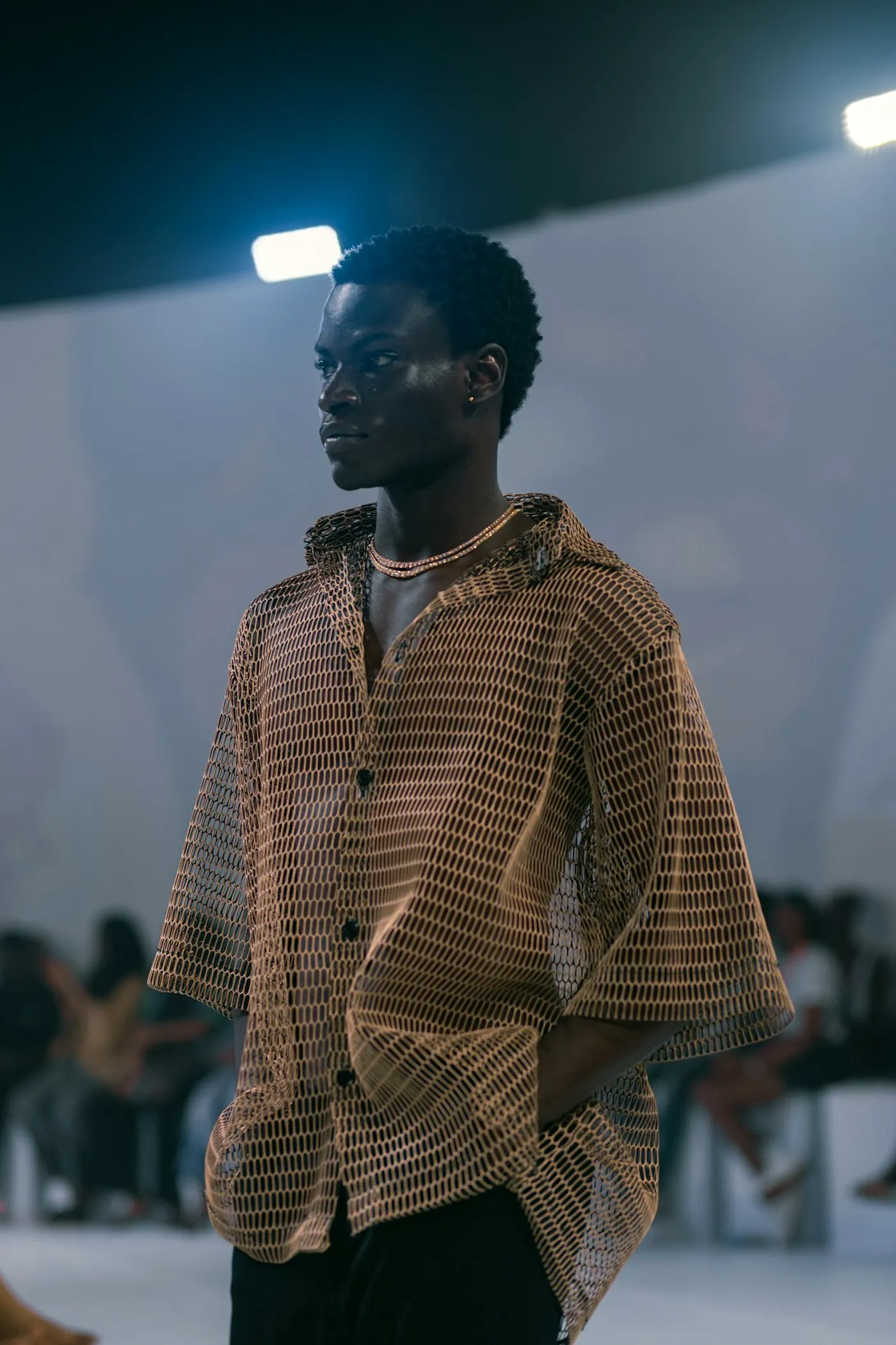A model in a striped shirt walking a runway in front of an audience.