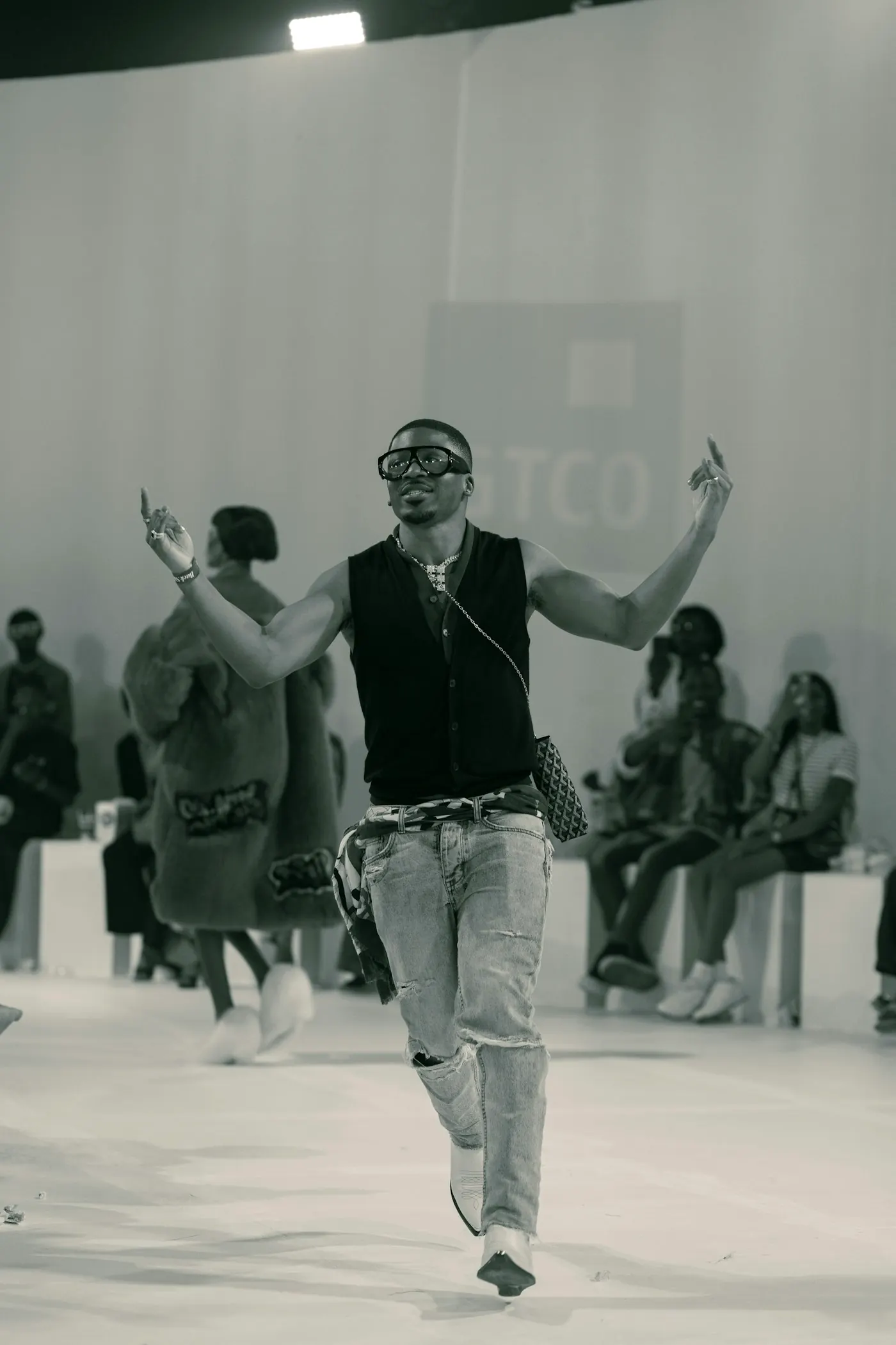 A man at the end of a runway with both arms raised.